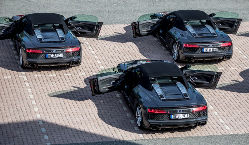 drei schwarze Audi R8 Modelle auf einem Parkplatz